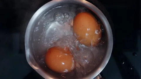 Two fresh chicken eggs boiling in stainless steel pan, close up, top view Stock Footage 150691478