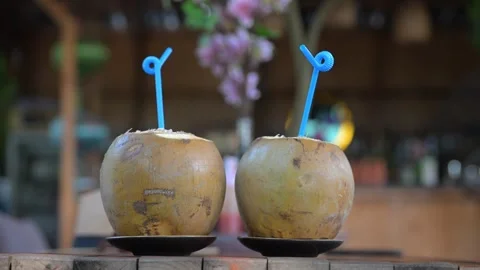 Two fresh coconuts with blue straws on a wooden table Видео 309635069