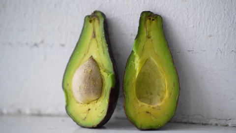 Two fresh cut avocado halves standing side by side against a clean white Stock Footage 344705001