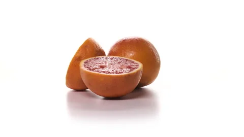 Two fresh cutted red oranges are spinning on white background. Freshly picked Stock Footage 148511175