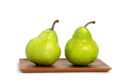 Two fresh Packham pears fruit above square wooden plate isolated on white bac Foto stock