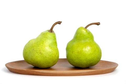 Two fresh Packham pears fruit above oval wooden plate isolated on white backg Stock Photos