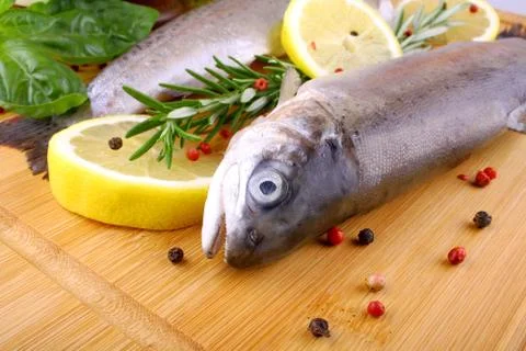 Two fresh rainbow trout with spices on bamboo board Stock Photos