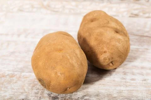 Two fresh, raw potatoes Stock Photos