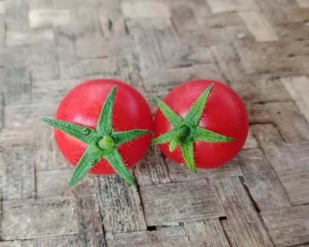 Two fresh red cherry tomatoes on a bamboo mat Stock Photos