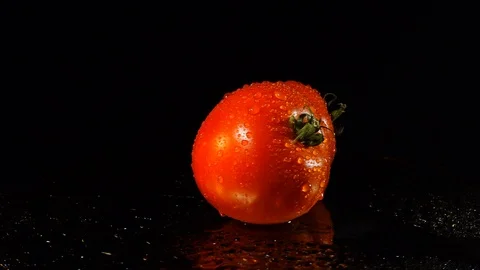 Two fresh ripe tomatoes on a dark mirror background. Tomatoes in water spray  스톡 동영상 93435248