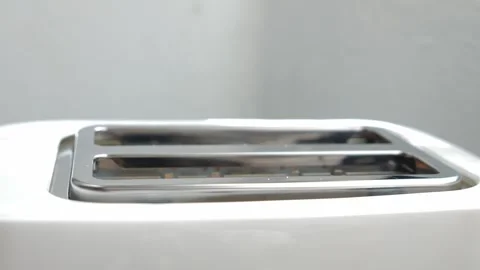Two fresh slices of bread lowering into a modern white kitchen toaster to be Stock Footage 329757602