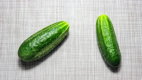 Two fresh whole cucumbers move around the table. Stock Footage 157921462