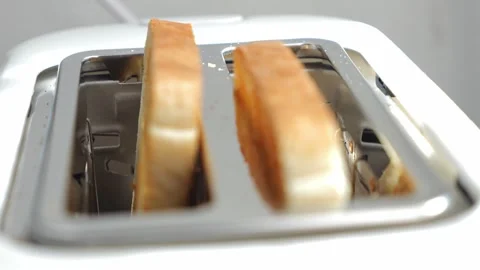 Two freshly toasted slices of bread slowly pop up from an electric toaster after Stock Footage 329757943