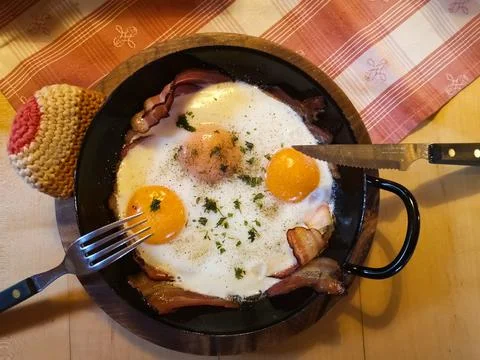 Two fried eggs and bacon in a pan to breakfast on vacation Stock Photos