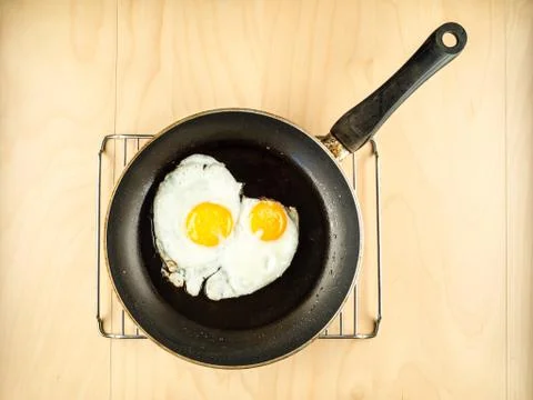 Two fried eggs on the black pan, simple top view Stock Photos