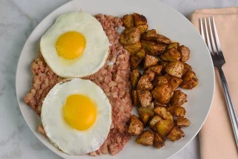 Two fried eggs  with corn beef hash and home fries Stock Photos