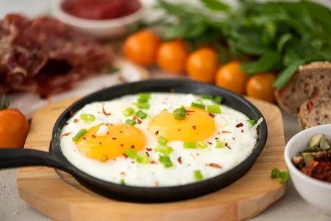Two fried eggs with herbs and spices in a small skillet Stock Photos