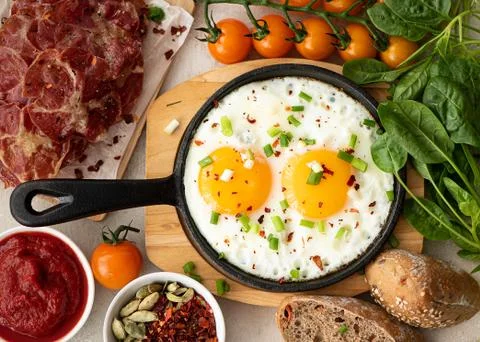 Two fried eggs with herbs and spices in a small skillet Stock Photos