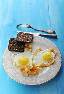 Two fried eggs with pepper and two slices of rye bread on a plate, knife and  Stock Photos