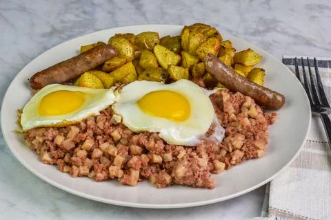 Two fried eggs  served with corn beef hash and  sausage Stock Photos