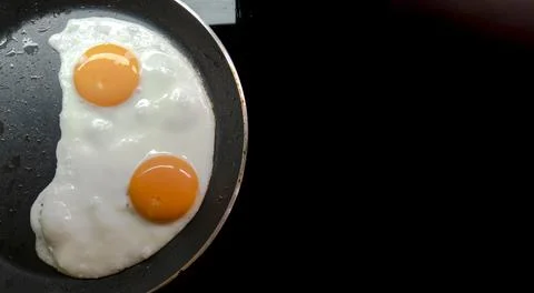 Two fried eggs in a teplon pan. Stock Photos
