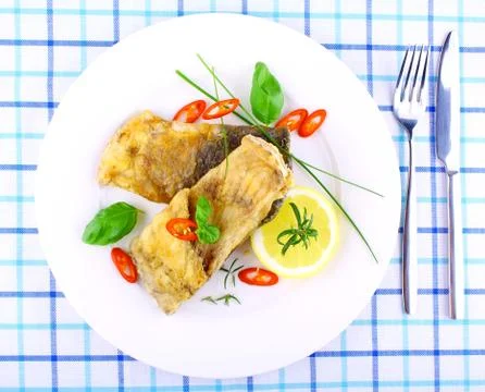 Two fried fish fillets with lemon slice on white plate Stock Photos
