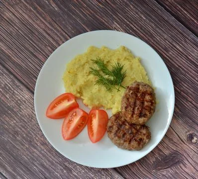 Two fried meat cutlets, mashed potatoes with herbs and tomato slices on a l.. Stock Photos