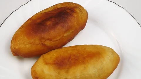 Two fried pie on a white plate with a gold rim.Homemade pastries with filling. 스톡 동영상 128701006