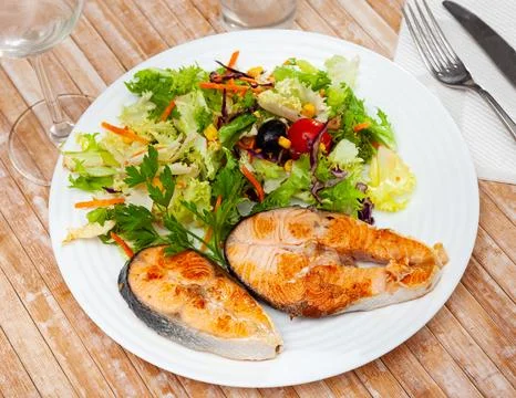 Two fried salmon steaks with vegetable salad Stock Photos