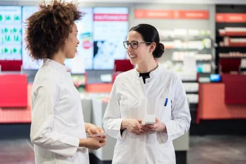 Two friendly colleagues talking while working together as pharmacists Stock Photos