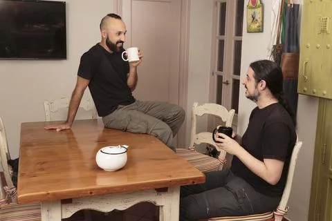 Two friendly young men drinking a hot beverage together Stock Photos