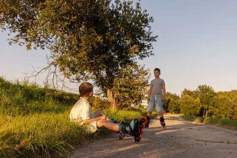 Two friends are having fun inline skating on a path surrounded by greenery... Stock Photos
