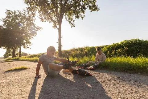 Two friends are inline skating in a sunny park. They are having fun spendin.. Stock Photos
