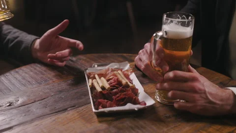 Two friends are relaxing in a pub after work talking and drinking beer. Close up Stock Footage 237748293
