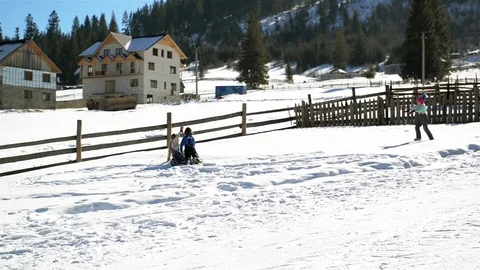 Two Friends are Rolling Huge Snowball up the Hill and the Third Girl is Running Stock Footage 73055214