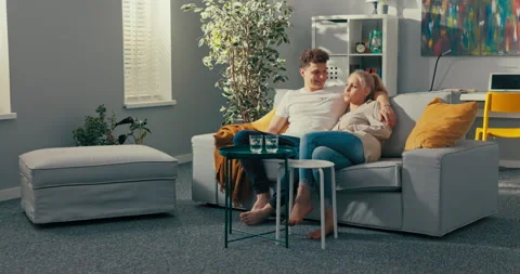 Two friends are sitting on a couch, they look at each other smile, man with 動画素材 161734241