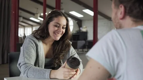 Two friends are sitting at the table in cafe, drinking coffee-to-go in paper Stock Footage