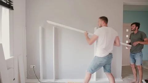 Two friends assembling the shelf, do the repairs. Man helping to his friend Video stock 74819999