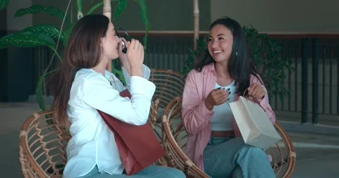 Two friends on bench showcasing new purchases sharing joy of shopping. Joy of Stock Footage 271008555