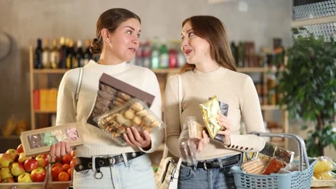 Two friends buy various sweets together - cookies and nougat in a grocery Stock Footage 341378838