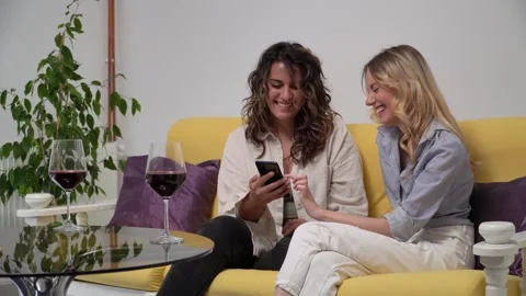 Two friends casually dressed are having fun while checking the phone Video stock 278482603