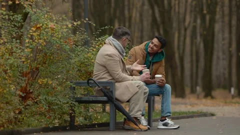 Two friends of different ages are having a conversation in autumn park. Stock Footage 271325749