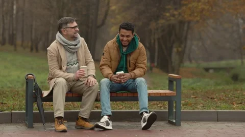 Two friends of different ages are having a conversation in autumn park. Stock Footage 271325769