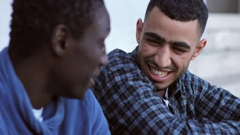 Two friends from different cultures talk and laugh in the city center Stock Footage 218595382
