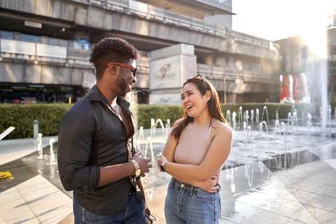 Two friends of different ethnicities chatting in a shopping mall Stock Photos