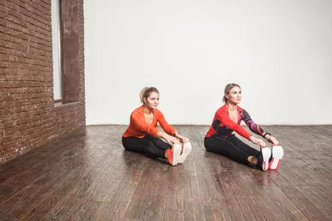 Two friends doingf orward bend exercise in loft interior room Fotos de archivo