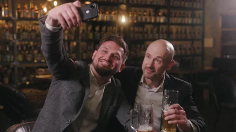 Two friends dressed in jackets and shirts drinking beer and relaxing in a pub Stock Footage 237604686