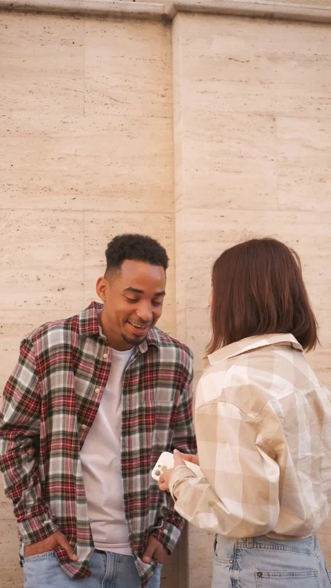 Two friends engaged in a lively conversation near a textured stone wall in an Stock Footage 315277984