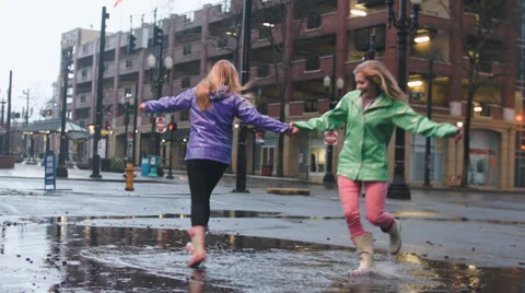 Two Friends Enjoy The Rain, Dance And Twirl In Big Puddle Stock Footage 36598087