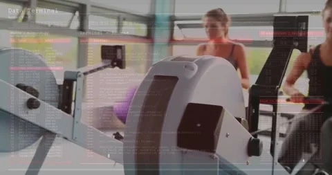 Two friends exercising on cardio machines in modern gym, with code overlay Stock Footage 325706285