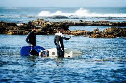 Two friends in front of the waves ready to surf Stock Photos
