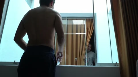 Two friends giving toothpaste through the window of two hotel rooms in the morni Stock Footage 197079007