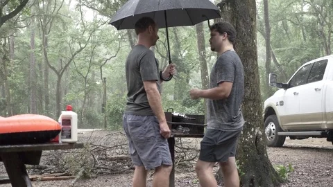 Two Friends Grilling Outside While it Rains Stock Footage 80539586