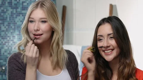 Two friends having fun while preparing theire make up for the day in front of Stock Footage 76775875